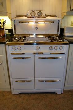 an old fashioned stove in a kitchen with white cabinets