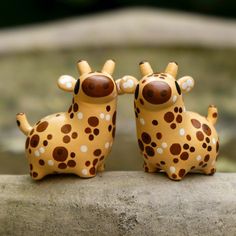 two ceramic giraffes sitting on top of a rock