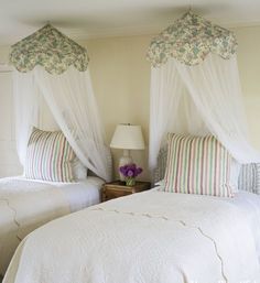 two beds in a bedroom with white covers and pillows