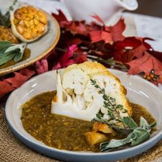 a bowl of soup with cauliflower in it on a table next to other dishes