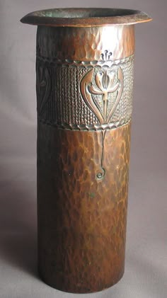 a metal container with a flower design on the top and bottom, sitting on a gray surface