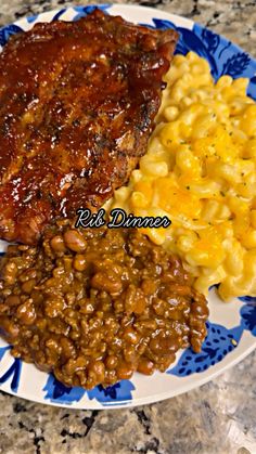 a plate with meat, macaroni and cheese on it next to some beans