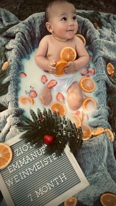 a baby sitting in a bath filled with oranges