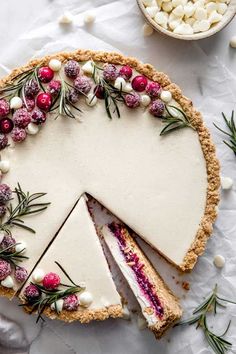 a cheesecake with cranberry sauce and white chocolate chips on top is cut into slices