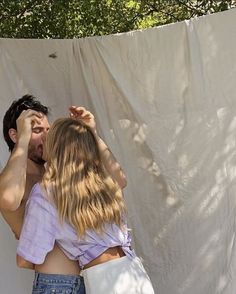 a man and woman standing next to each other in front of a white sheeted wall