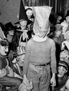 an old black and white photo with many people dressed up in halloween costumes, including one wearing a paper bag on his head