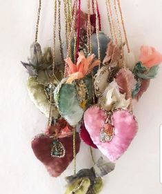 several heart shaped ornaments hanging from chains on a wall ornament with flowers and leaves attached to them