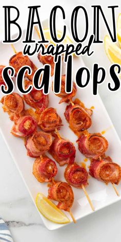 bacon wrapped scallops on a white plate with lemon wedges next to it