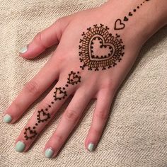 a henna tattoo on someone's hand with hearts and stars in the middle