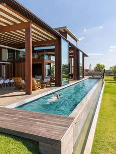 an outdoor swimming pool in the middle of a grassy area next to a large house