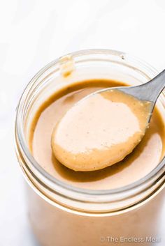 a spoon full of peanut butter sitting in a jar