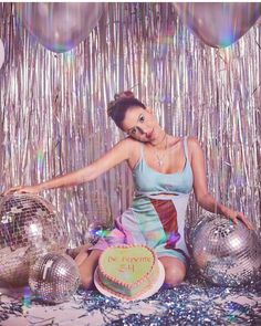 a woman sitting on the floor in front of disco balls