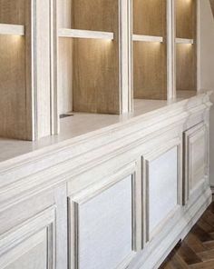 an empty room with white cabinets and wood flooring on the walls, along with wooden parquet floors