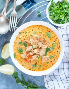 a bowl of soup with chicken and cilantro on the side