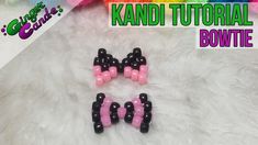 two black and pink bowtie shaped beads sitting on top of a white fur rug