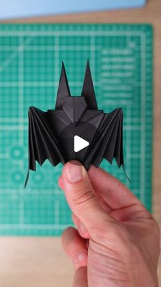 a person holding up a black origami bat