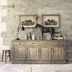 a horse statue on top of a wooden cabinet next to two pictures hanging on the wall