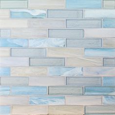 a white and blue tile wall with some light colored tiles on the bottom half of it