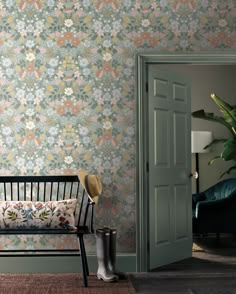 a bench sitting in front of a green door next to a wall with flowers on it