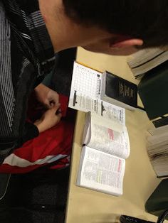 a man sitting at a desk with books and papers on top of it, next to a calculator