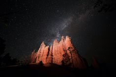 the night sky is filled with stars and bright lights, as well as silhouettes of rock formations