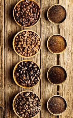 five bowls filled with different types of coffee beans and ground coffee on top of a wooden table