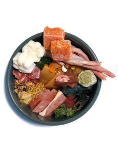 a black bowl filled with assorted meats and vegetables