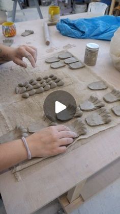 a woman is making pottery on a table with her hands and fingers touching the clay