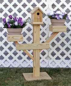 a wooden birdhouse with two flower pots on it