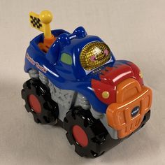 a toy truck with an orange, blue and red engine is on a white surface