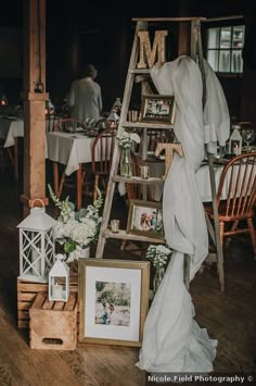 a ladder with pictures and flowers on it in the middle of a dining room at a wedding