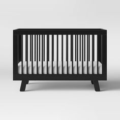 a black crib with white sheets on it