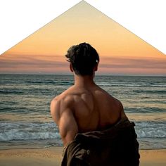 a man standing on top of a sandy beach next to the ocean with his back turned