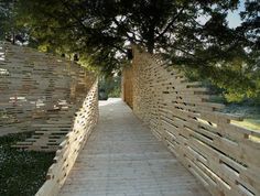 a wooden walkway that has been constructed into the shape of a wall and trees on both sides