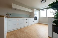 an empty kitchen with wooden floors and white cabinets