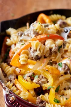 a spoon full of pasta with sausage and peppers