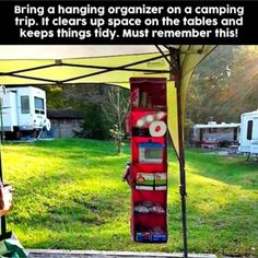 a woman sitting in a green chair under a tent next to a camper trailer