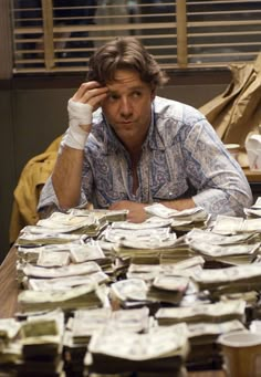 a man sitting at a table covered in stacks of papers and plates with napkins on them