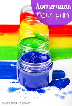 two jars filled with blue and green paint on top of a rainbow colored tablecloth