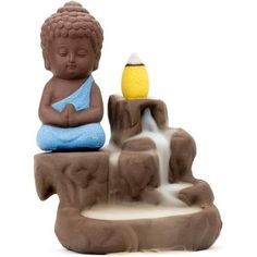 a buddha statue sitting on top of a fountain with a yellow ball in it's hand