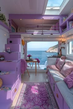 a living room with purple walls and flooring next to the ocean in front of a window