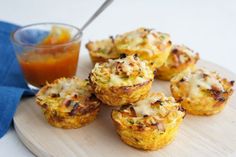 several small muffins on a cutting board next to a cup of orange juice