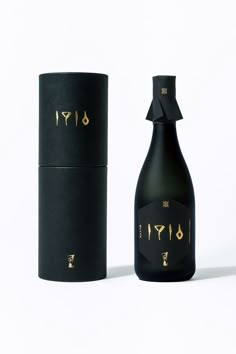 a black bottle with gold writing on it next to a box