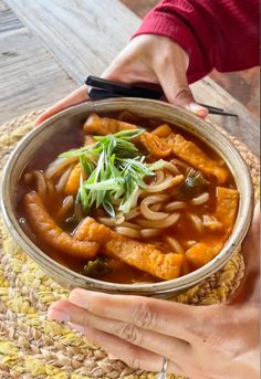 a person holding a bowl of food on top of a table