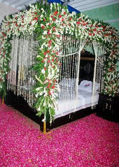 a bed covered in white and red flowers on top of a pink carpeted floor