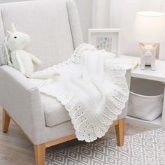 a white crocheted blanket sitting on top of a chair next to a lamp