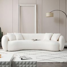 a white couch sitting on top of a wooden floor next to a table and lamp