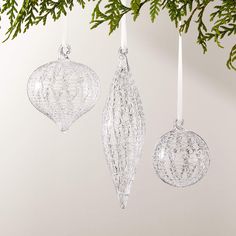 three glass ornaments hanging from a christmas tree