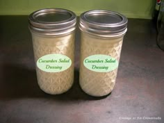 two jars with labels on them sitting on a counter