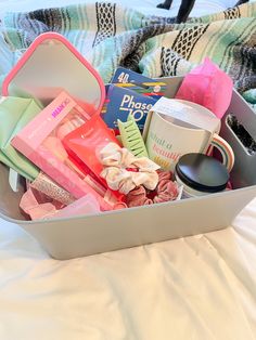 a suitcase filled with lots of different items on top of a white bed covered in blankets